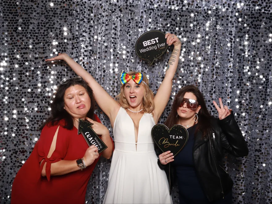 Bridal party posing with props at an Orlando wedding photo booth on a silver sequin backdrop