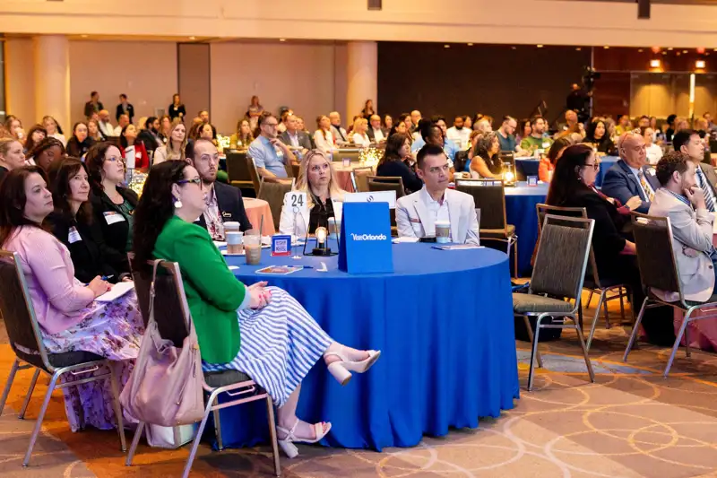 Attendees seated at round tables during the forum.