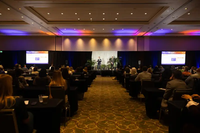 Audience members seated during an onstage presentation.