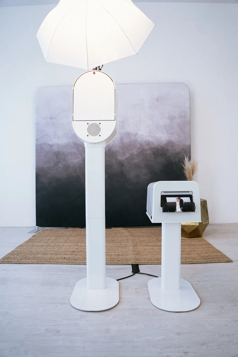 Minimal white wedding photo booth setup with a clean gradient backdrop