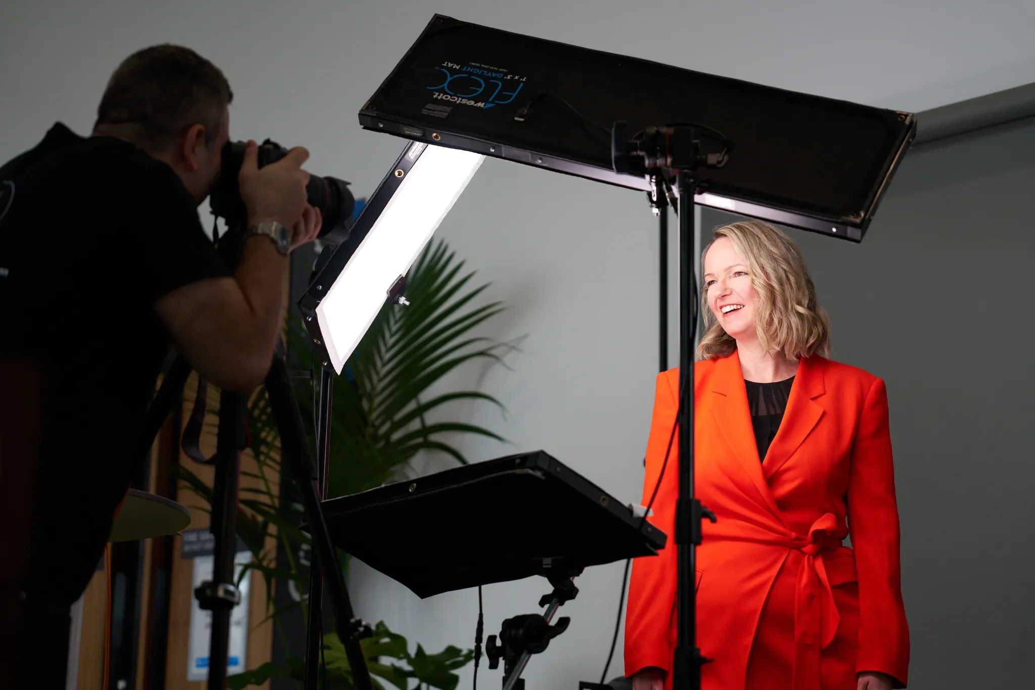 Photographer taking a professional portrait of a woman in an orange jacket