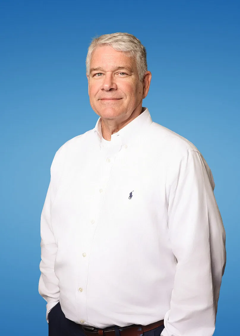 Clean corporate headshot of a man in a white shirt on a blue studio backdrop