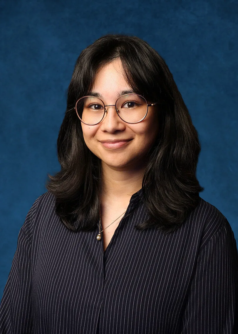 Professional corporate headshot of an attendee wearing glasses on a blue backdrop