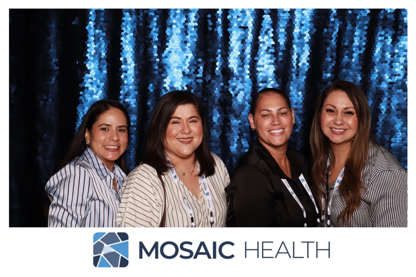Four Mosaic Health retreat guests posing against the blue sequin photo booth backdrop