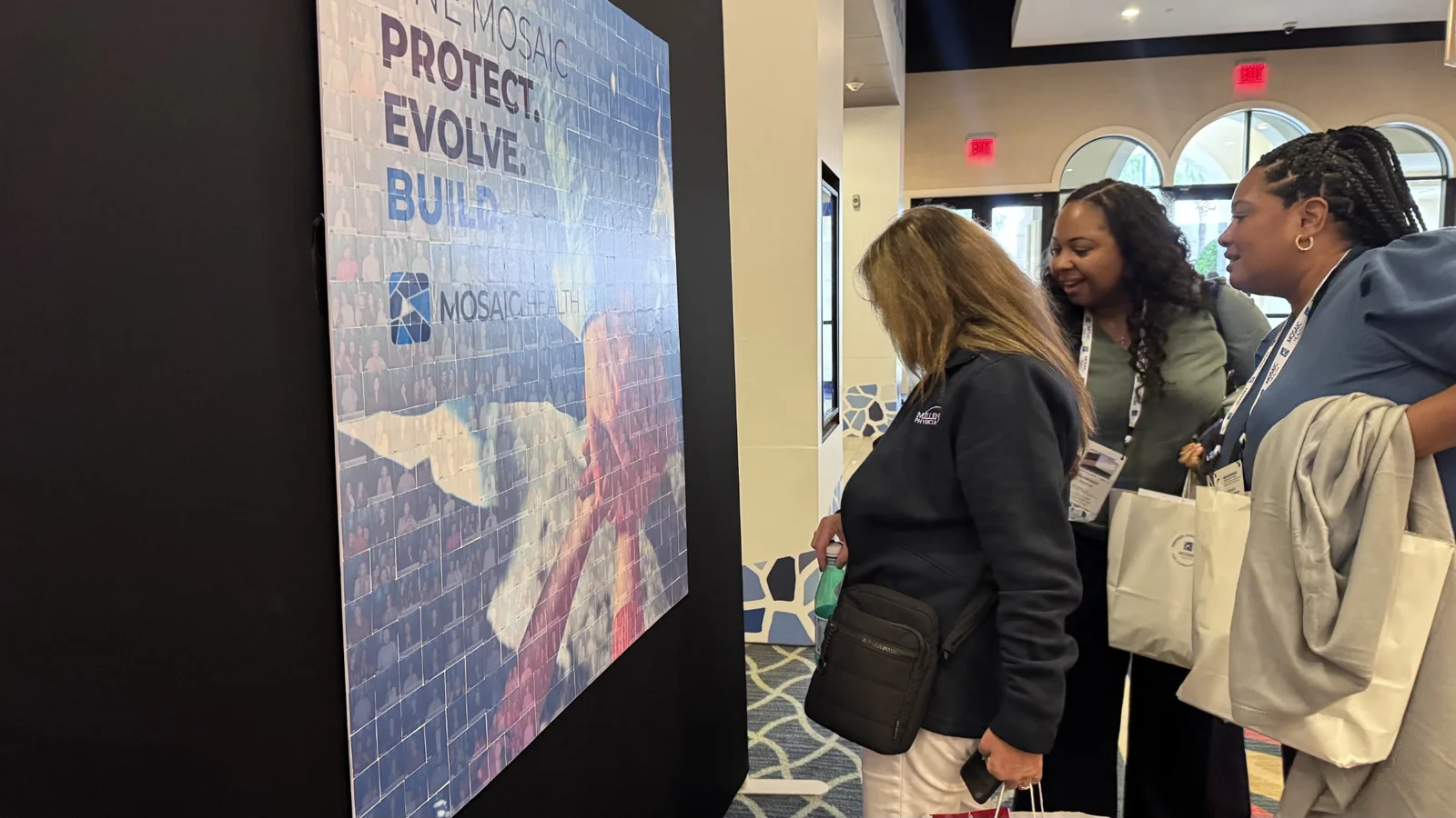 Leadership retreat guests examining the Mosaic Health photo mosaic wall