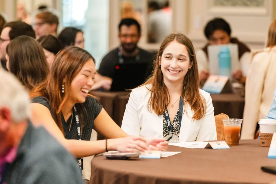 Event detail photography of attendees seated at tables during a corporate networking moment