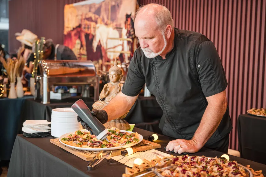Event detail photography of a chef plating food at a catering station during a corporate event
