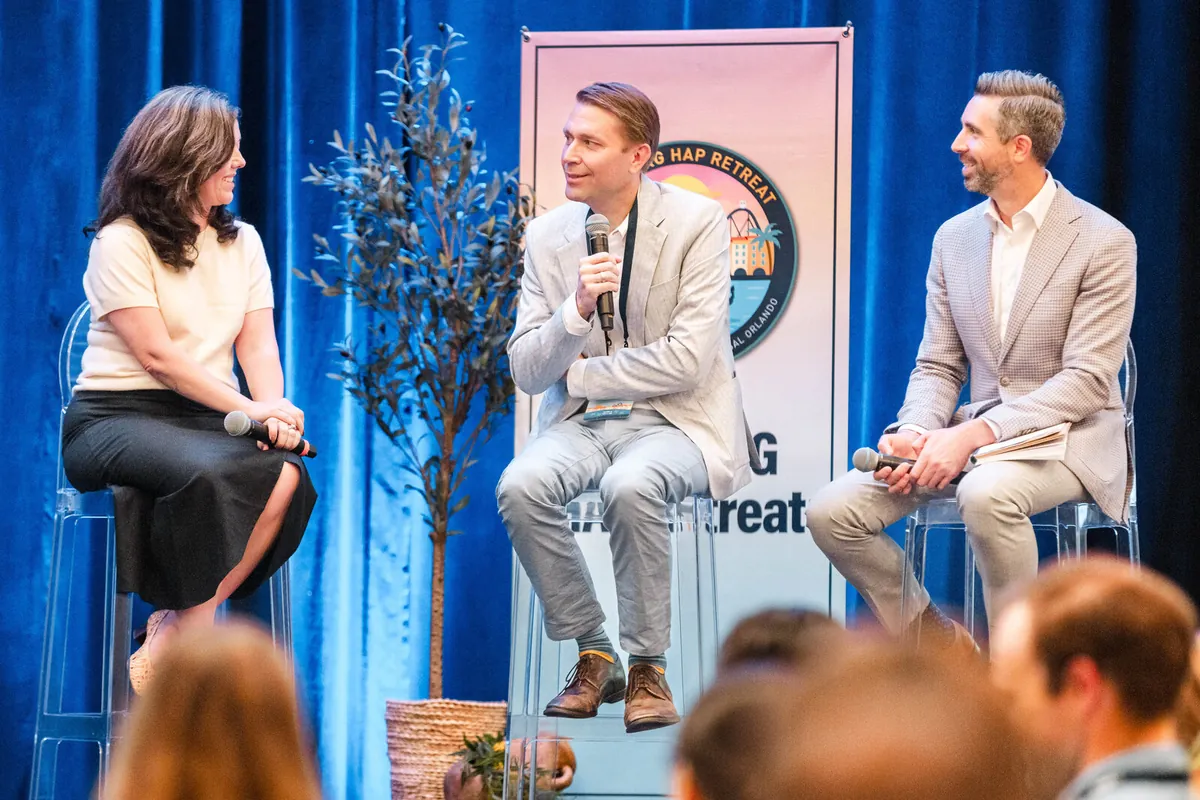 Orlando conference photography of a fireside-style stage session with branded backdrop and audience