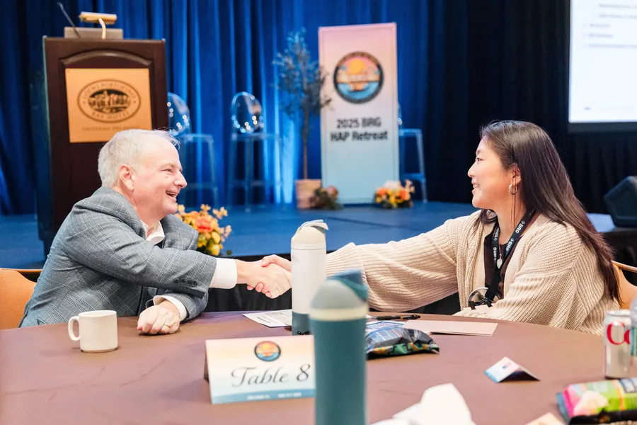 Corporate event photography of a fireside-style stage conversation with branded backdrop