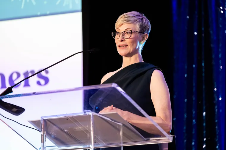 Keynote photography of a speaker presenting at a clear acrylic podium under dramatic stage lighting