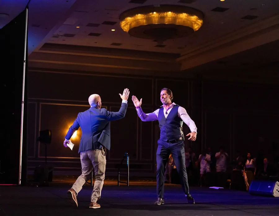 Event photography of an energetic celebratory moment between two presenters on stage