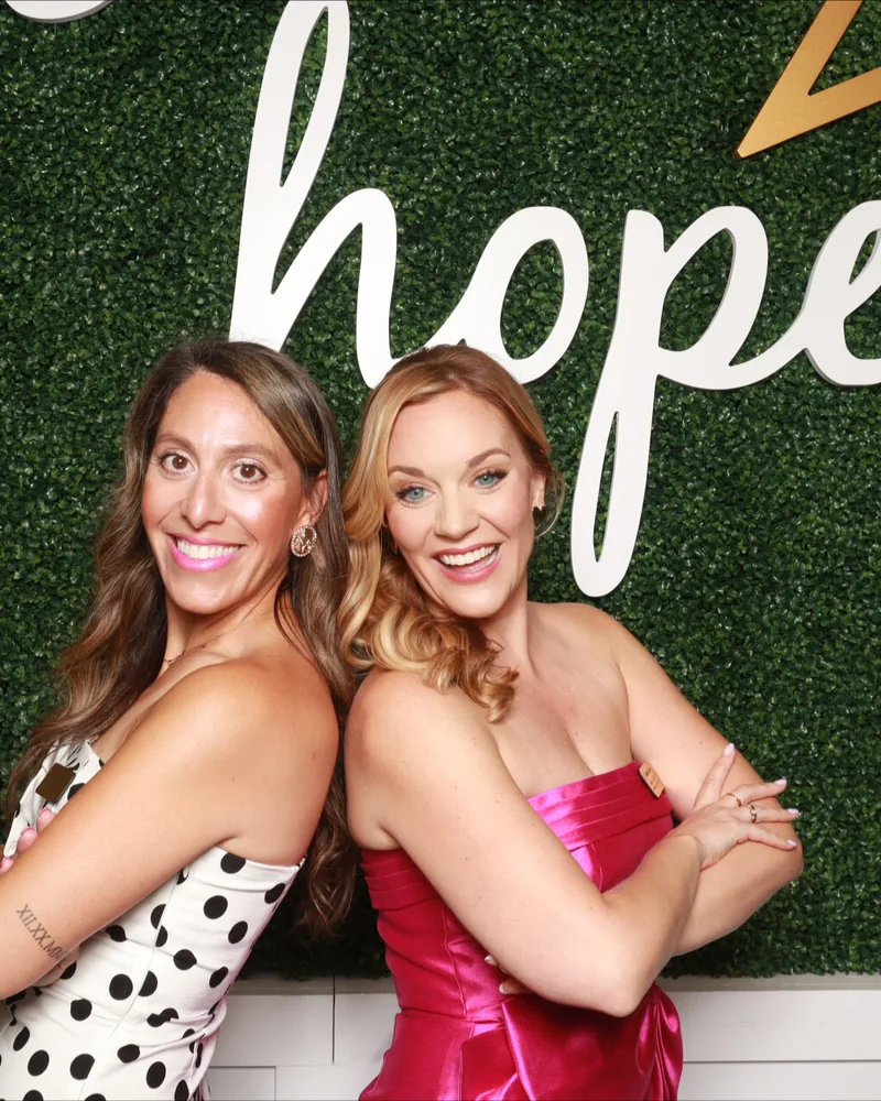 Two guests posing at a greenery backdrop during an Orlando charity gala photo booth