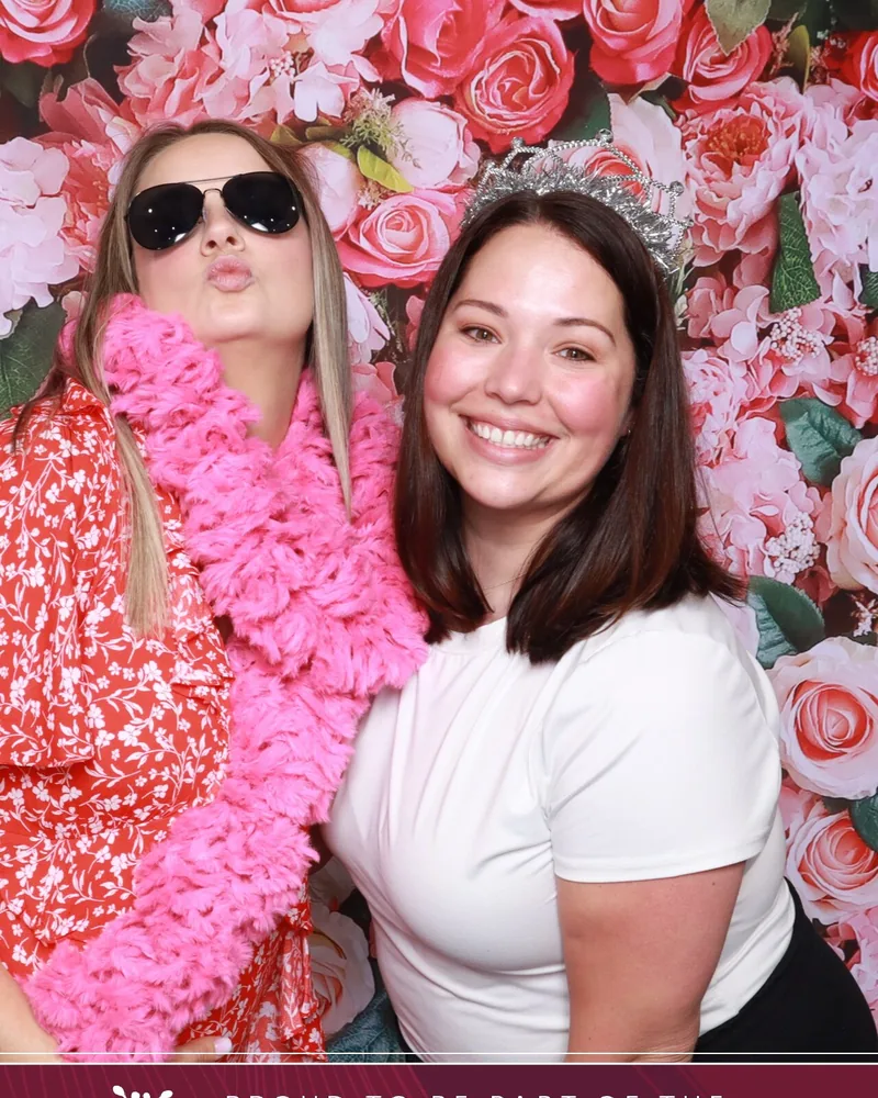 Guests posing at a pink floral branded backdrop in an Orlando photo booth