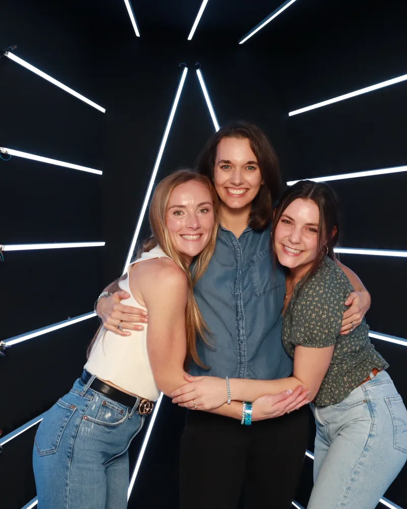 Friends posing together in a Pro DSLR open-air photo booth with light-streak walls at an Orlando event