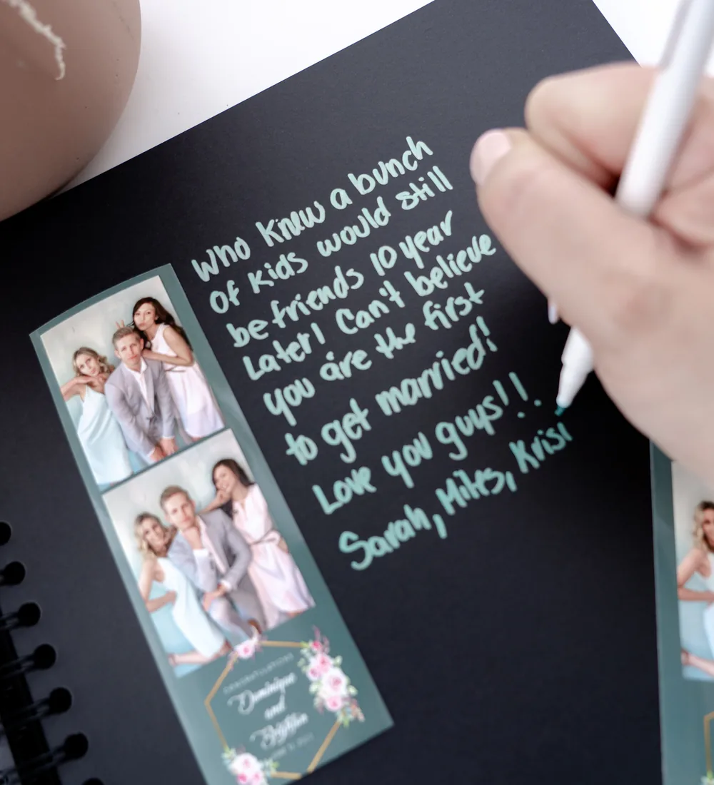 Guests signing a Pro DSLR photo booth memory book with photo strips and a handwritten note at a wedding
