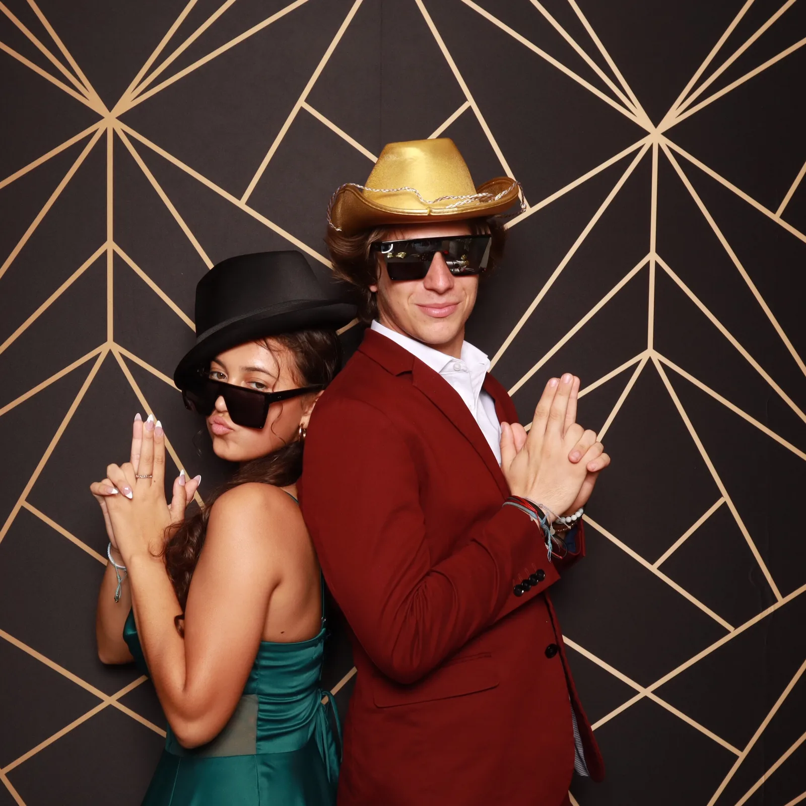 Two guests posing with props against a styled backdrop at a Strata Booth photo booth, available to pair with roaming photography