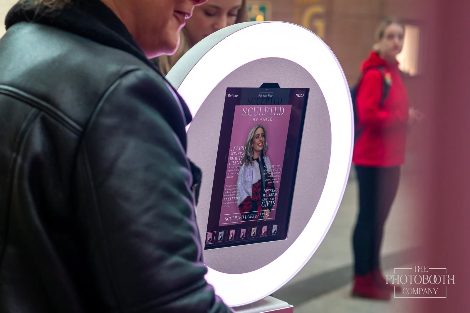 Guest at an iPad roamer booth with a ring light showing a branded magazine-style photo overlay at a corporate event