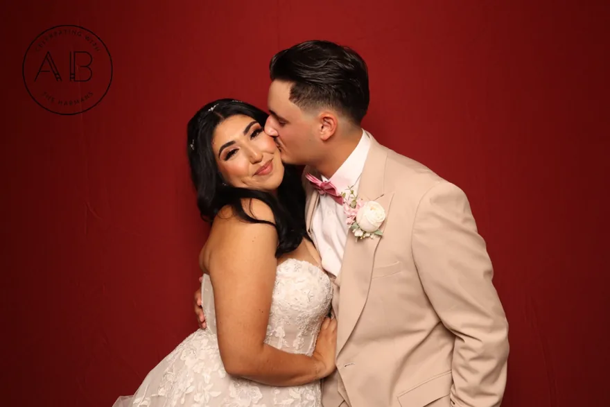 Bride and groom in a romantic Orlando wedding photo booth portrait on a red backdrop